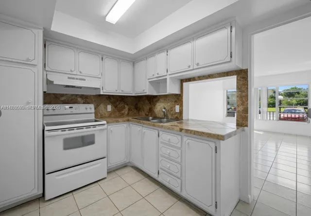 a kitchen with granite countertop white cabinets and white appliances
