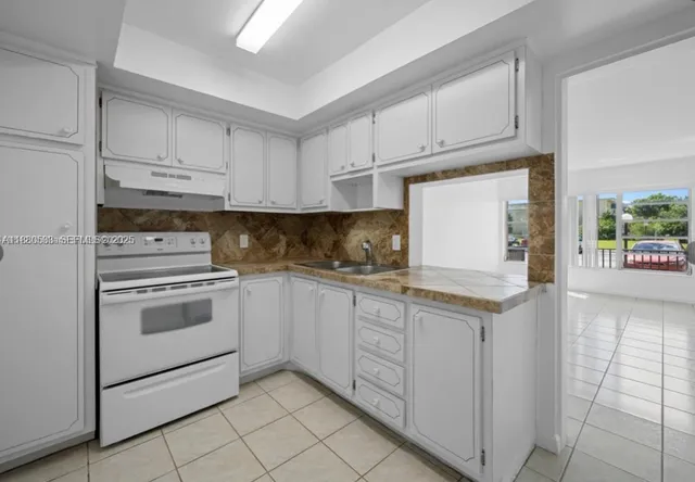 a kitchen with granite countertop white cabinets and white appliances