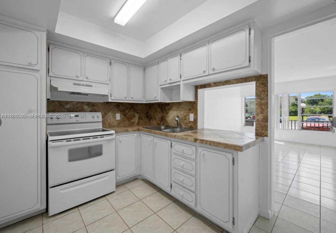 1400 Northeast 169th Street, Unit 115 Miami, FL 33162 - Photo 10 of 17 a kitchen with granite countertop white cabinets and white appliances