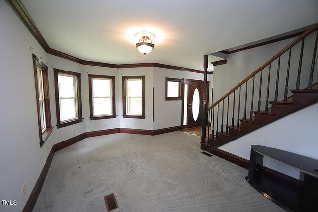 a view of an empty room with stairs and a window