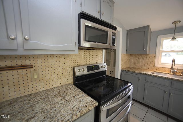 a kitchen with stainless steel appliances granite countertop a stove microwave and sink