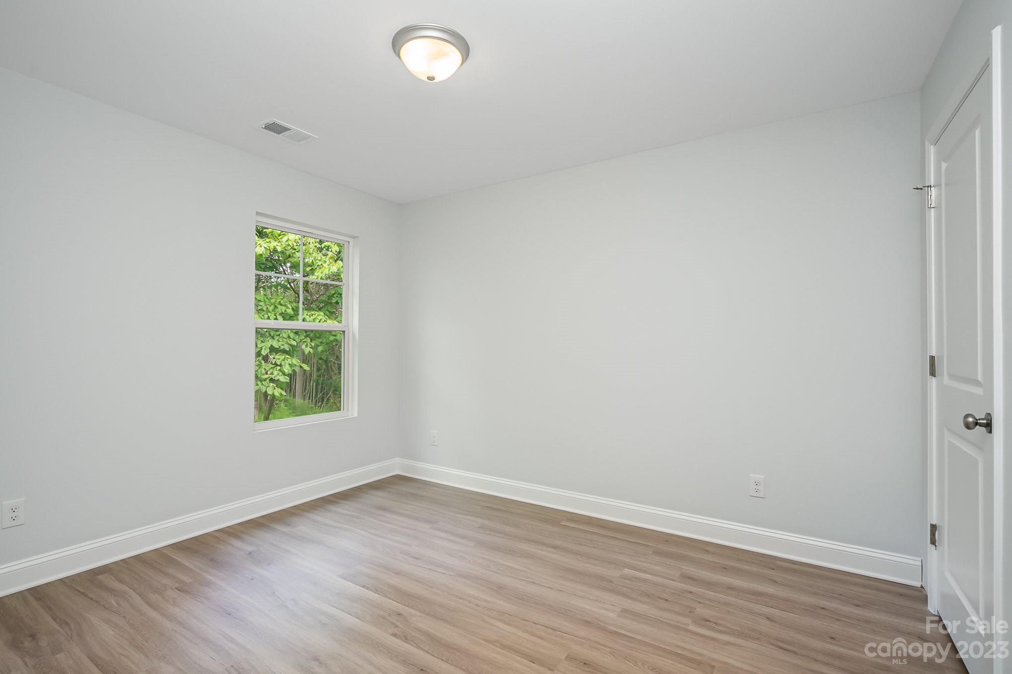 1016 Helms Road Charlotte, NC 28214 - Photo 32 of 39 an empty room with wooden floor and windows