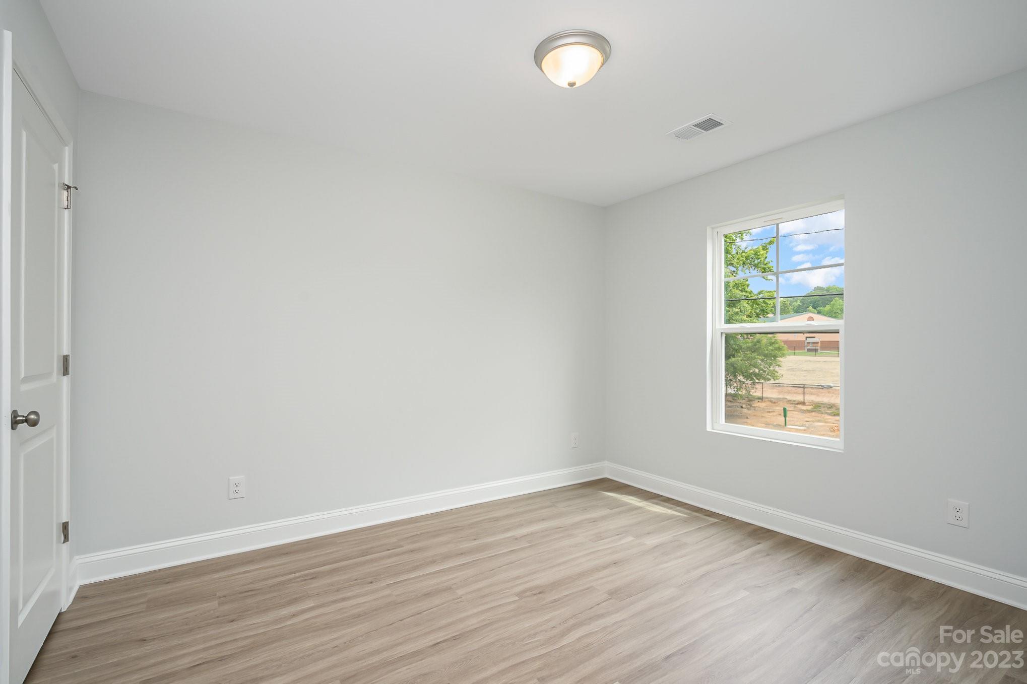 1016 Helms Road Charlotte, NC 28214 - Photo 35 of 39 an empty room with wooden floor and windows