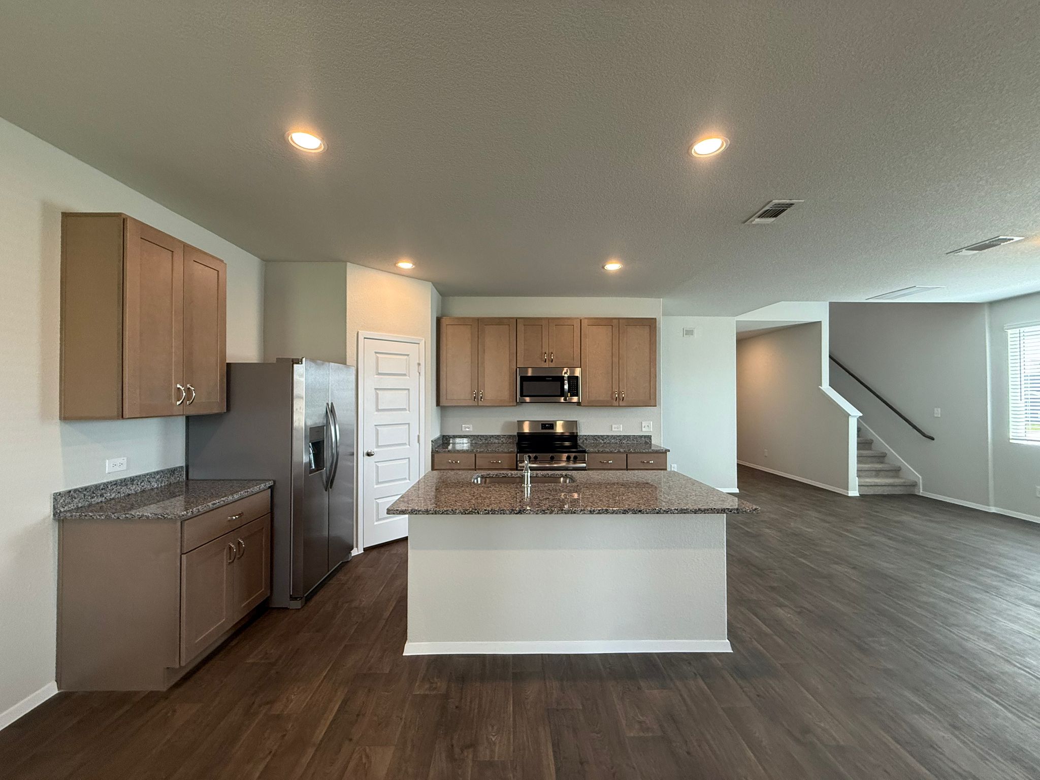 2601 Totley Road Pflugerville, TX 78660 - Photo 10 of 40 Kitchen with stainless steel appliances, dark wood-style flooring, dark stone countertops, a kitchen island with sink, and recessed lighting