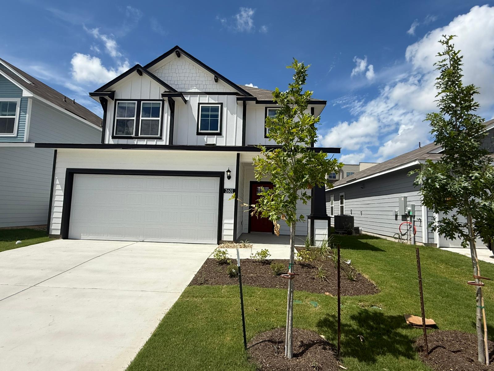 2601 Totley Road Pflugerville, TX 78660 - Photo 3 of 40 View of front of house with board and batten siding, an attached garage, a front lawn, and driveway