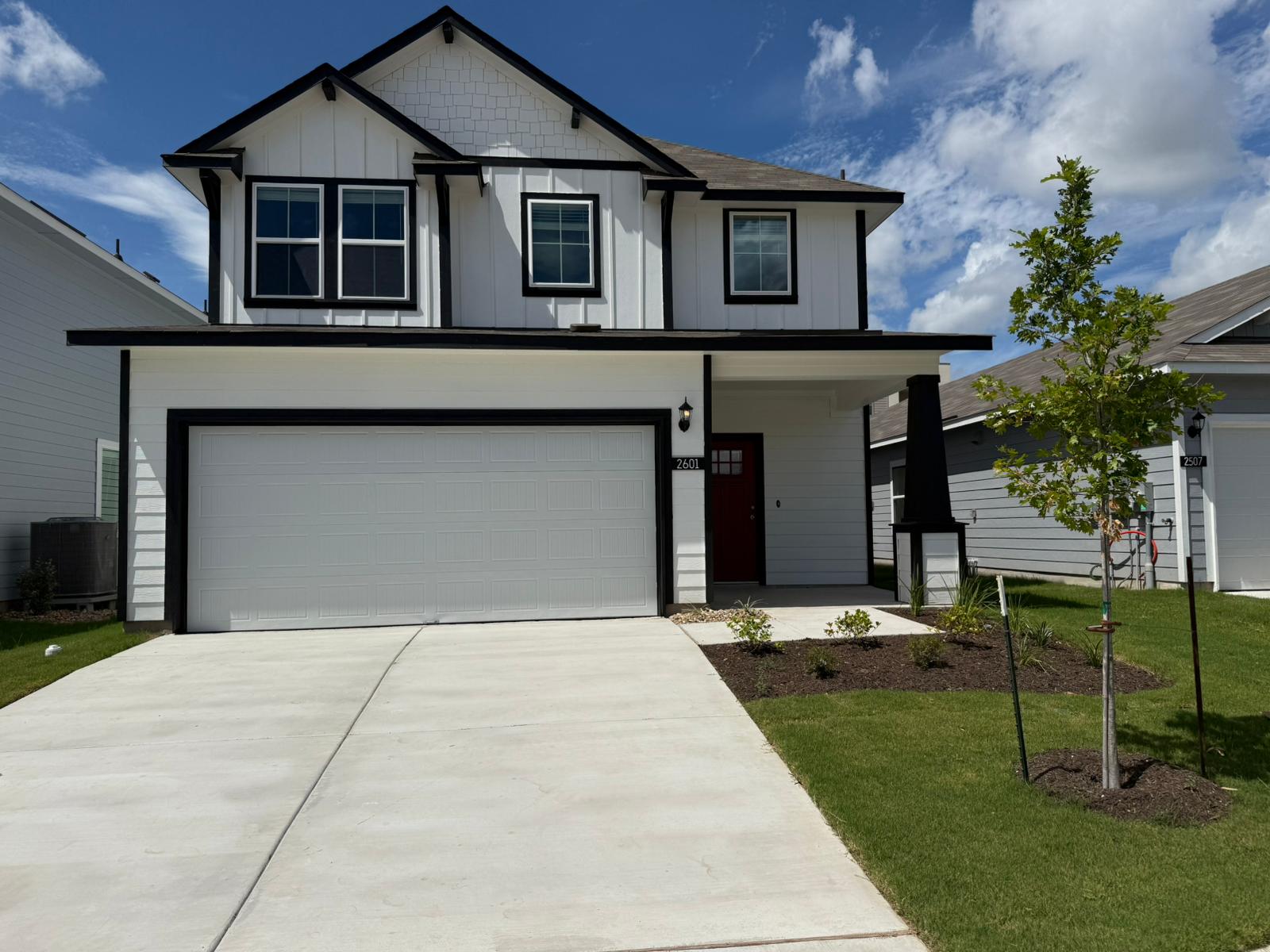 2601 Totley Road Pflugerville, TX 78660 - Photo 4 of 40 View of front facade with board and batten siding, a garage, a porch, a front yard, and concrete driveway