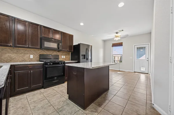 a kitchen with stainless steel appliances kitchen island granite countertop a refrigerator and a stove top oven