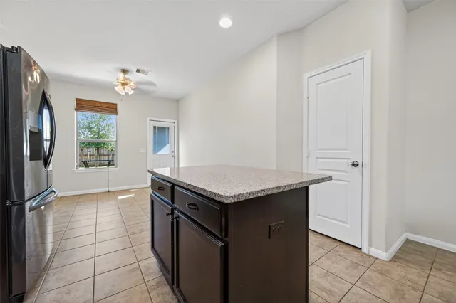an empty room with wooden floor chandelier fan and windows