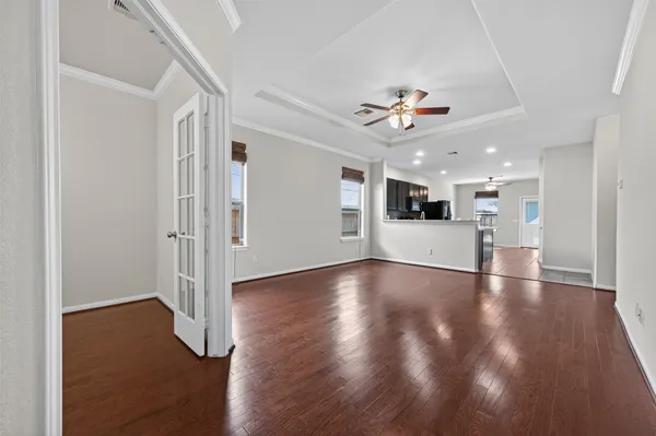 a view of an empty room with wooden floor and a ceiling fan