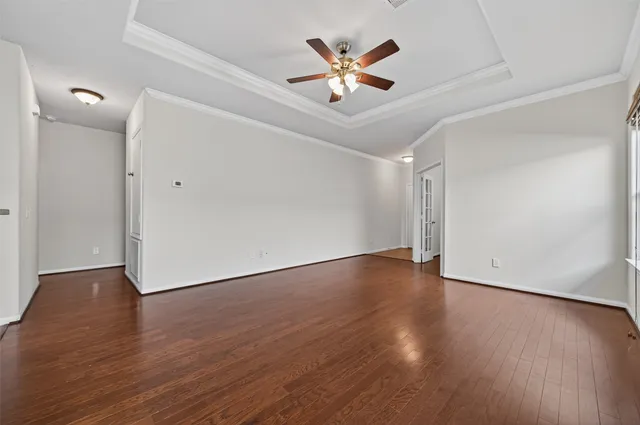 a view of an empty room with window and chandelier fan