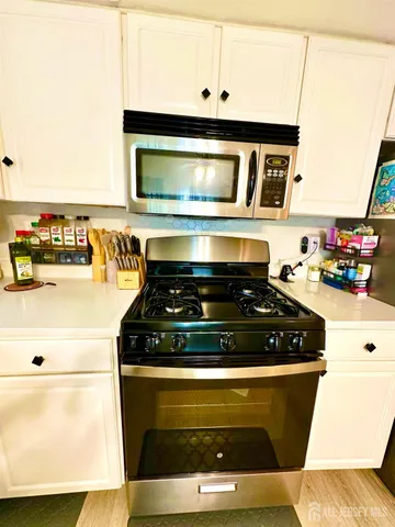 a kitchen with stainless steel appliances kitchen island granite countertop a table chairs refrigerator and microwave