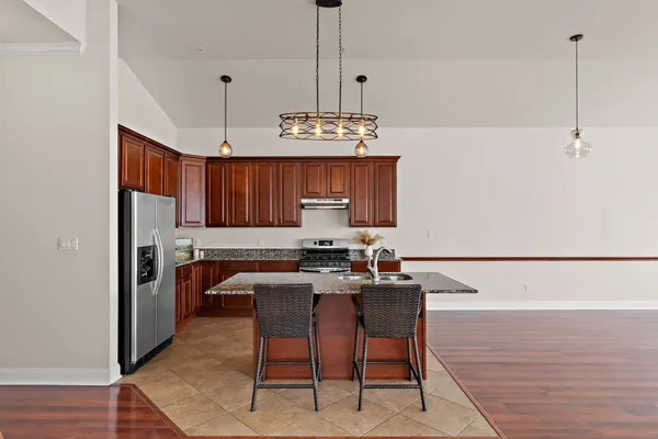 a kitchen with stainless steel appliances granite countertop a stove a refrigerator a sink dishwasher a dining table and chairs with wooden floor