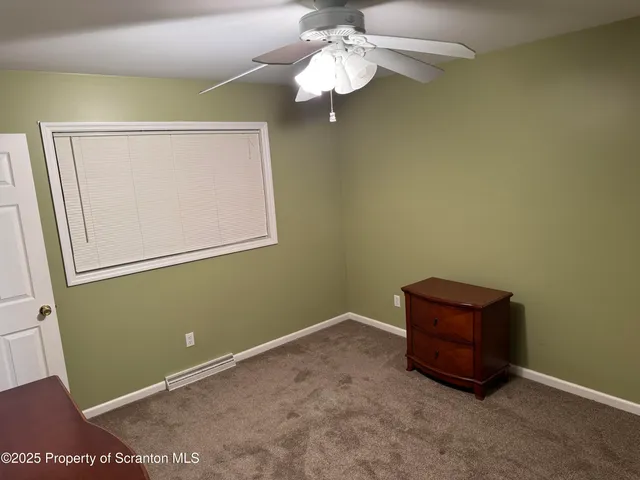 a room with a chandelier fan and a large window