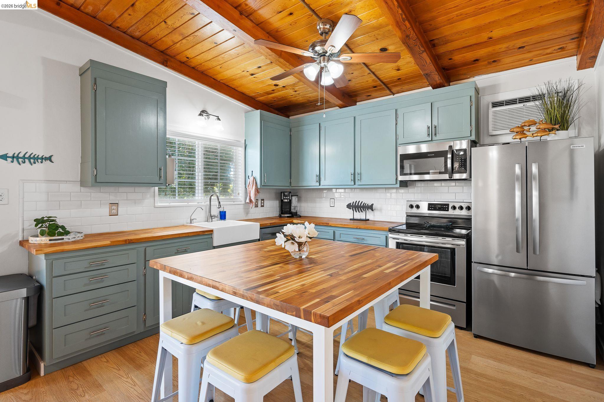 1704 Taylor Road Bethel Island, CA 94511 - Photo 26 of 73 Kitchen featuring a rustic wood-planked ceiling with exposed beams, light blue cabinetry, white subway tile backsplash, wood-finish countertops, and stainless steel appliances