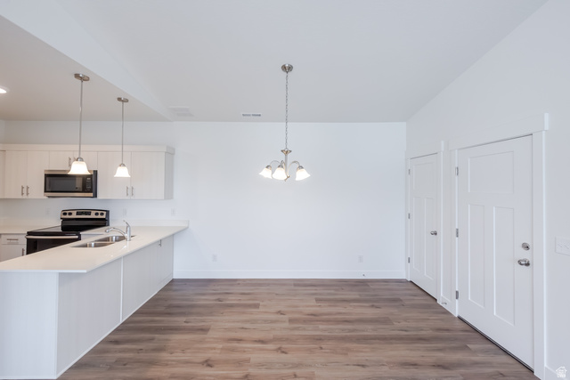 693 West 4500th South, Unit O301 Mapleton, UT 84664 - Photo 13 of 16 Kitchen with white cabinetry, a peninsula, stainless steel appliances, dark wood-type flooring, and a chandelier