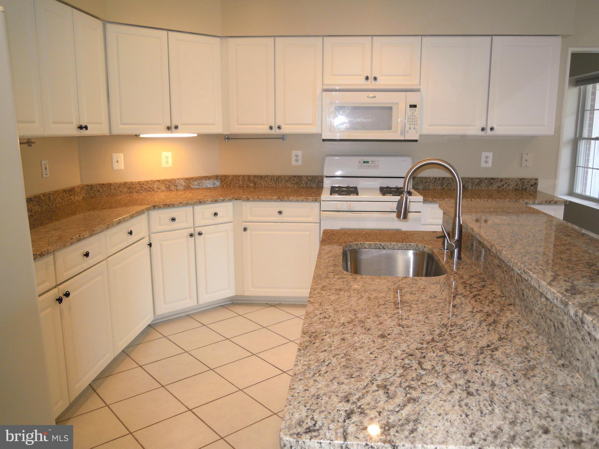 12000 Tralee Road, Unit 302 Lutherville-Timonium, MD 21093 - Photo 2 of 28 a kitchen with granite countertop white cabinets and stainless steel appliances