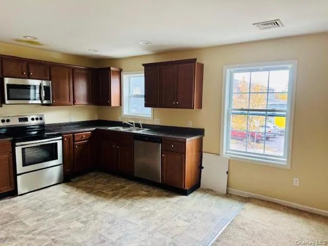 a large kitchen with stainless steel appliances granite countertop a stove a sink and a refrigerator