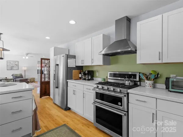 a kitchen with stainless steel appliances white cabinets and a stove top oven