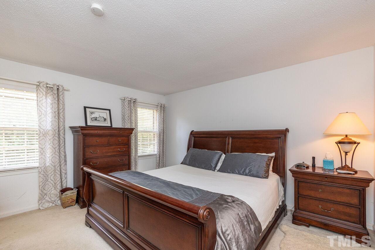 4808 Waybridge Court Raleigh, NC 27606 - Photo 18 of 29 a bedroom with a bed and a lamp on table window