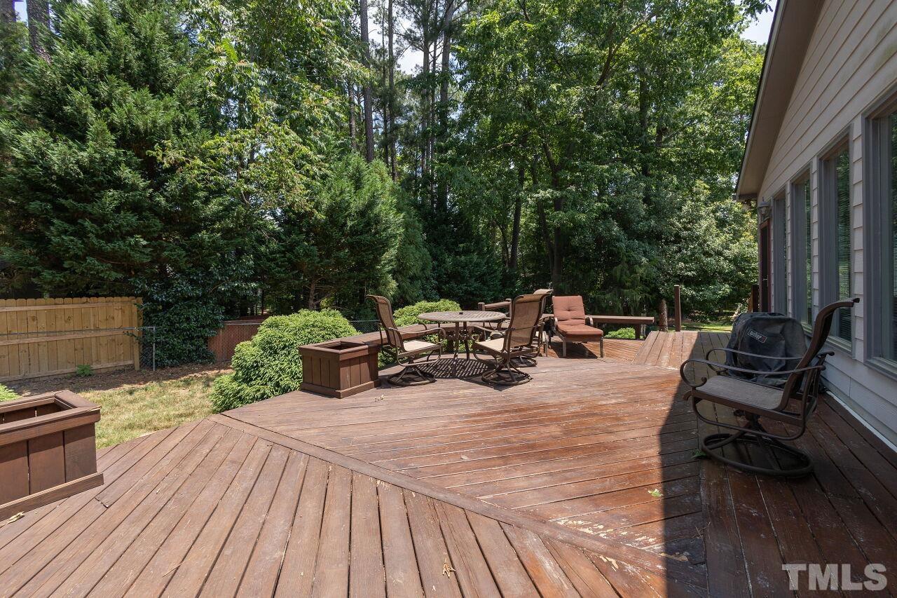 4808 Waybridge Court Raleigh, NC 27606 - Photo 26 of 29 a view of a patio with table and chairs barbeque grill with wooden floor and fence