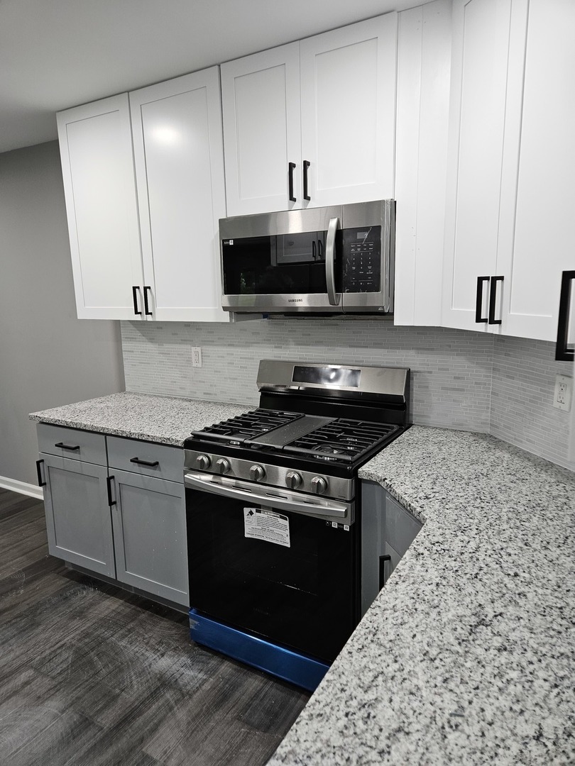 17612 Wright Street Lansing, IL 60438 - Photo 12 of 40 a kitchen with stainless steel appliances granite countertop a stove a sink and a microwave