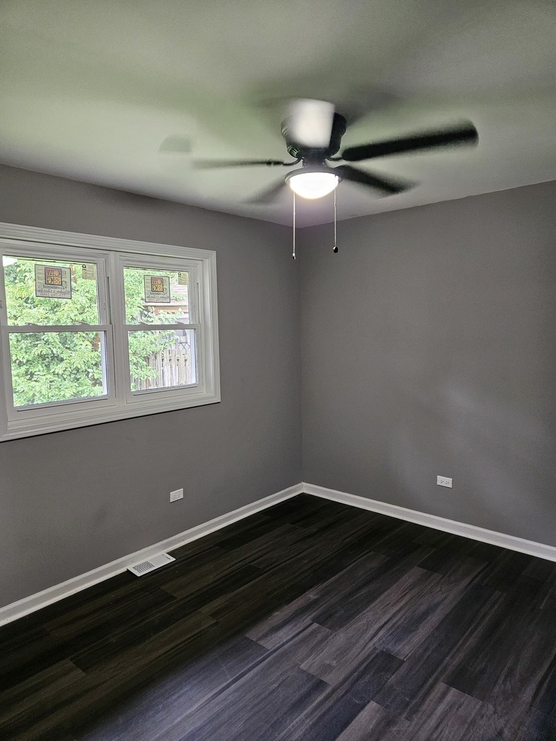 17612 Wright Street Lansing, IL 60438 - Photo 32 of 40 an empty room with wooden floor a ceiling fan and windows