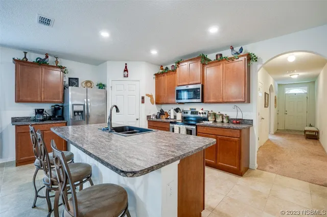 a kitchen with granite countertop stainless steel appliances a sink and a refrigerator