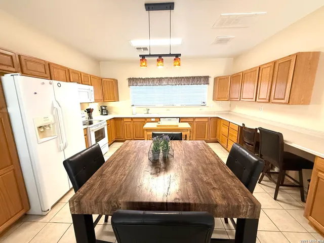 a kitchen with stainless steel appliances a dining table chairs and a refrigerator