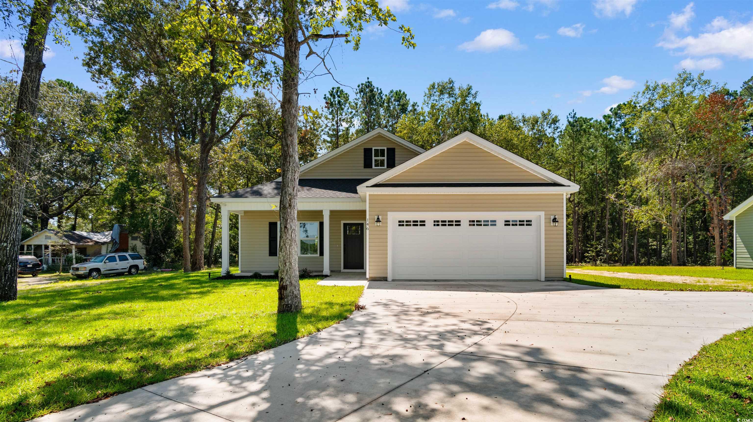 View of front of property featuring a front lawn, a porch, concrete driveway, and an attached garage