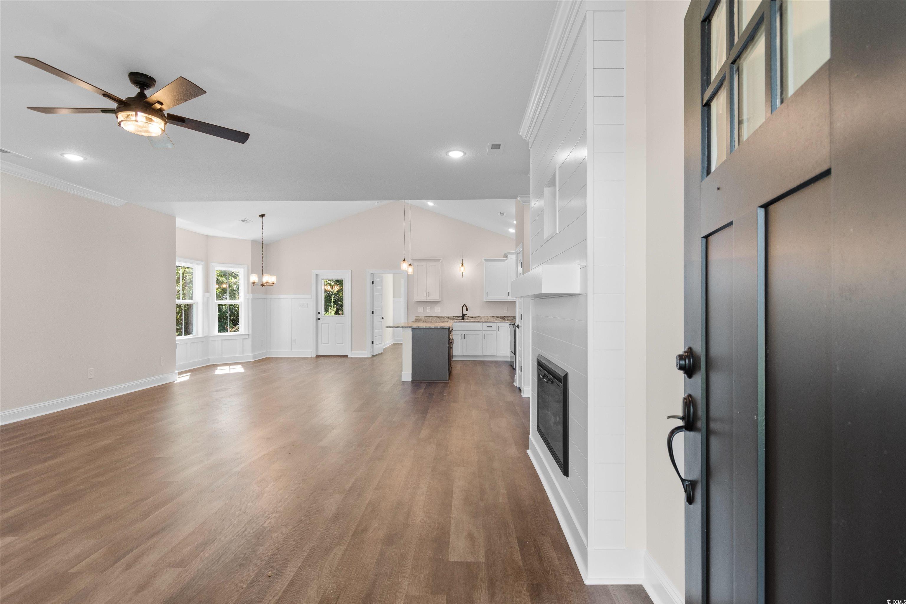146 Temple Drive Aynor, SC 29511 - Photo 2 of 40 Unfurnished living room featuring ceiling fan, a fireplace, dark wood-style floors, lofted ceiling, and a chandelier