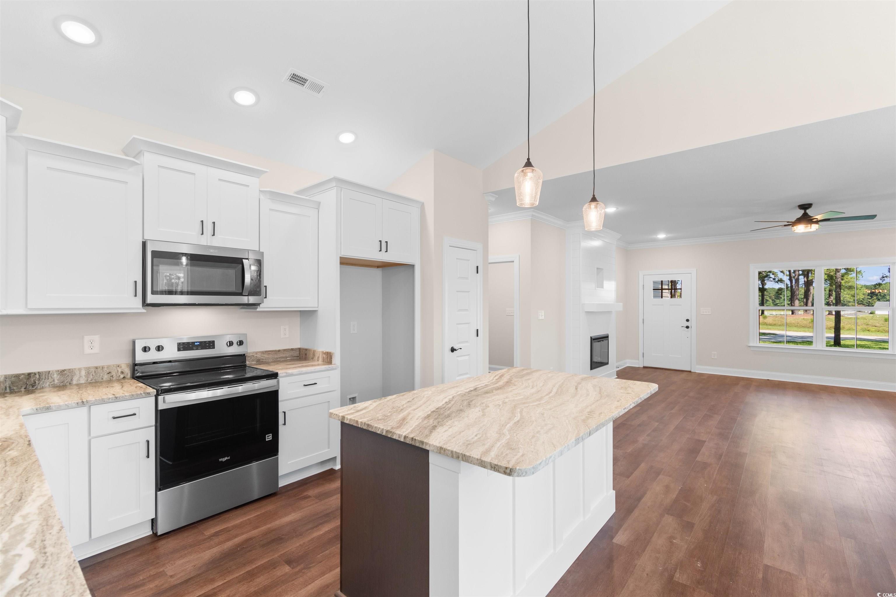 146 Temple Drive Aynor, SC 29511 - Photo 3 of 40 Kitchen with appliances with stainless steel finishes, a center island, white cabinets, ornamental molding, and vaulted ceiling