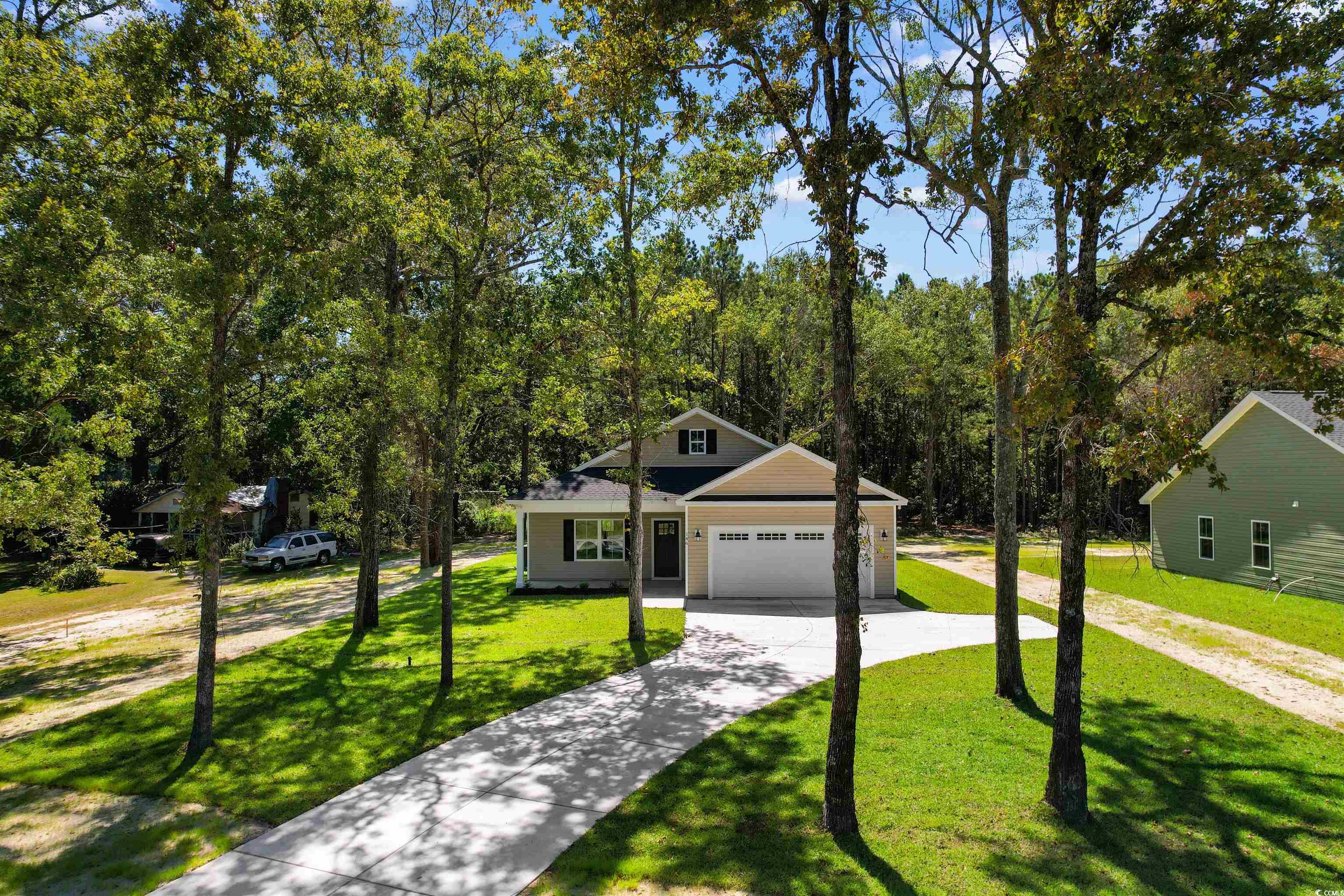 146 Temple Drive Aynor, SC 29511 - Photo 34 of 40 View of front of house with concrete driveway, a front yard, a garage, and a forest view