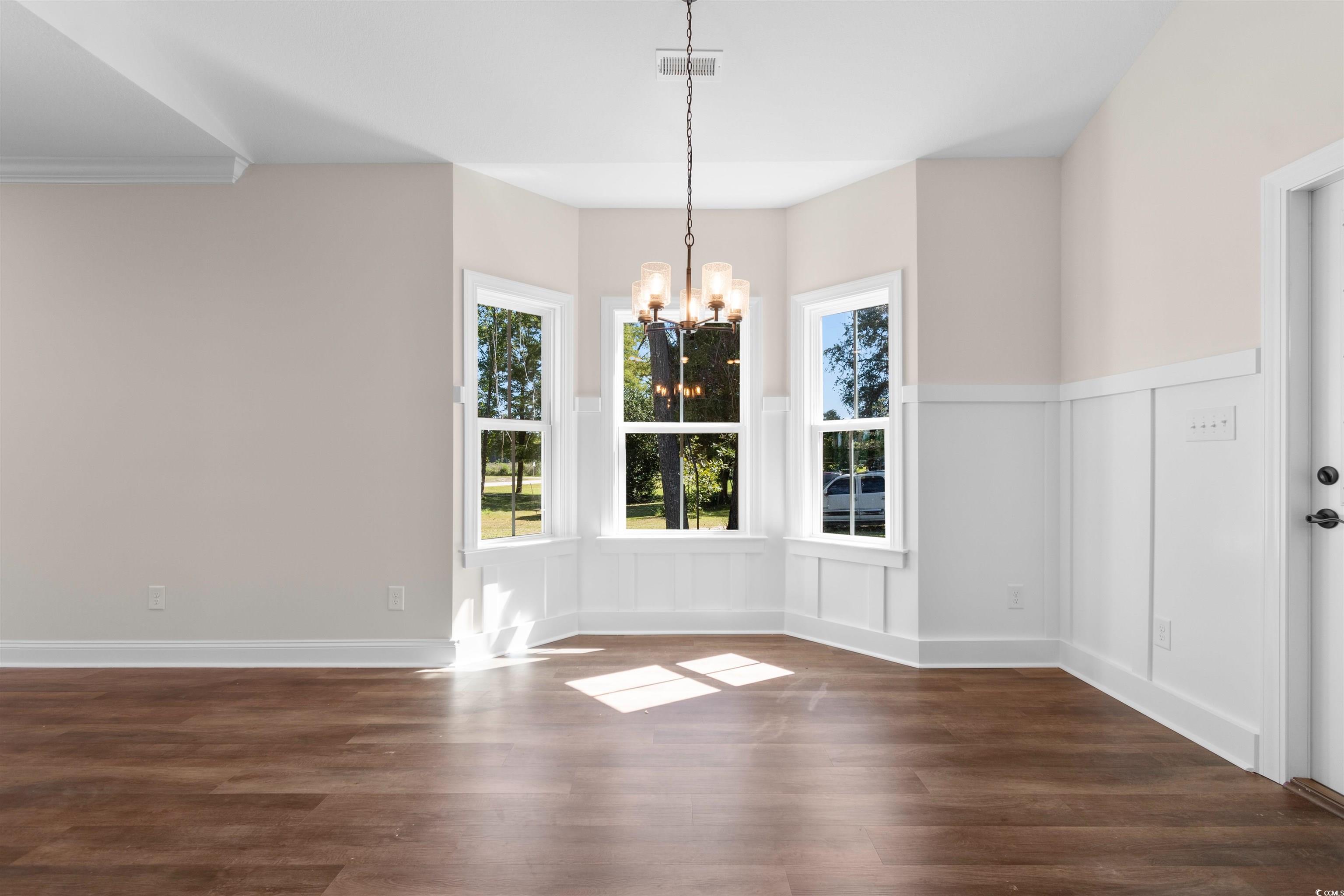 146 Temple Drive Aynor, SC 29511 - Photo 7 of 40 Unfurnished dining area featuring dark wood finished floors, a chandelier, and a decorative wall