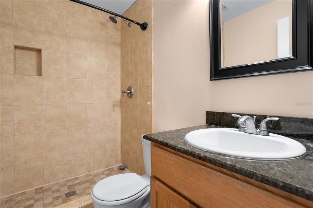 7337 Cedar Creek Court, Unit 75 Winter Park, FL 32792 - Photo 15 of 26 a bathroom with a granite countertop sink toilet a mirror and shower