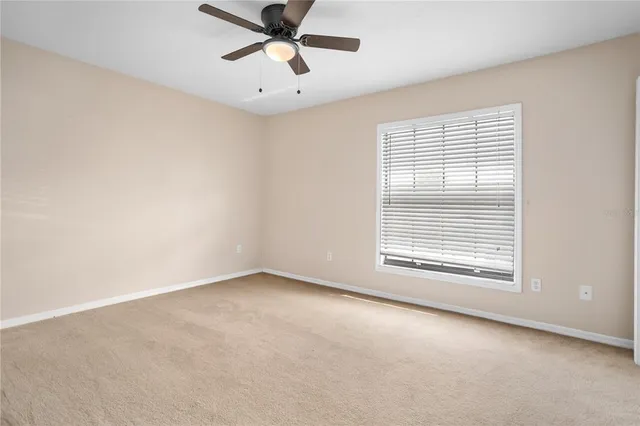 an empty room with a window and a fan