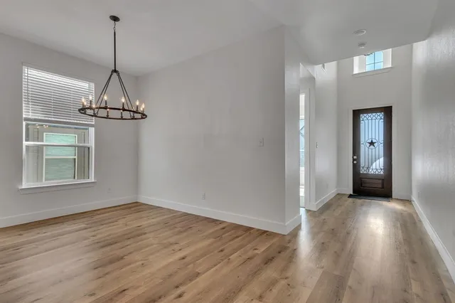 a view of a room with wooden floor chandelier and windows