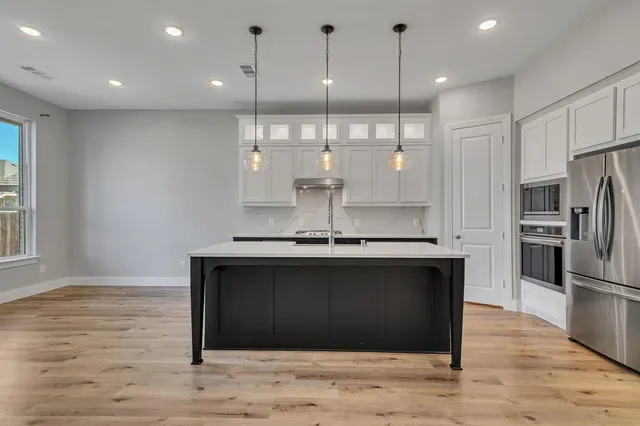 a kitchen with stainless steel appliances granite countertop a refrigerator a sink a stove and a wooden floors