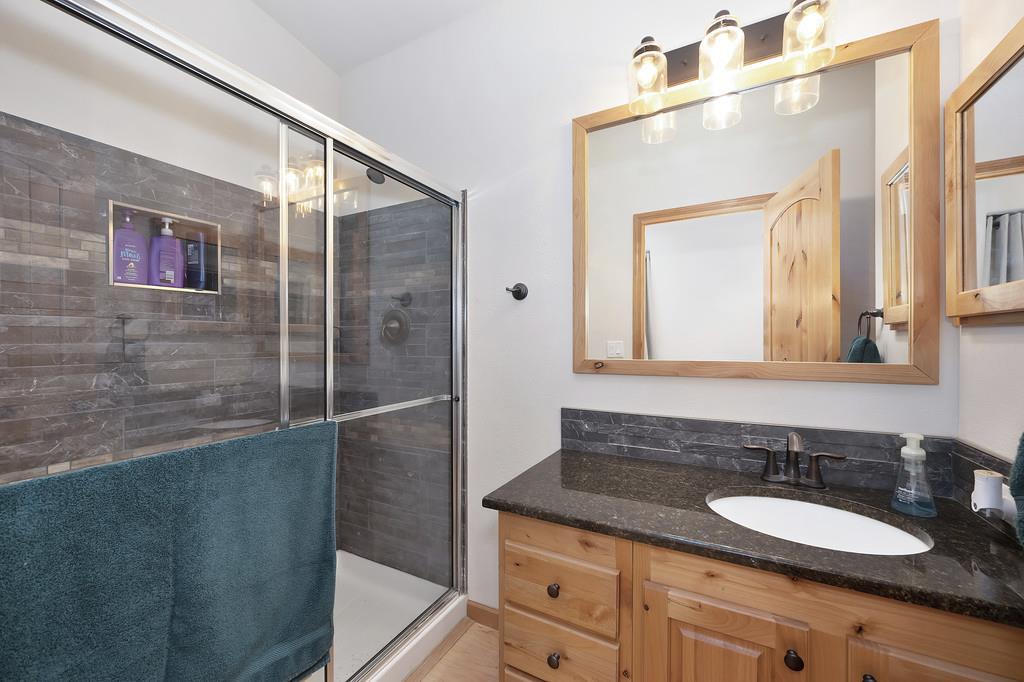 5060 Chestnut Court Georgetown, CA 95634 - Photo 38 of 65 a bathroom with a granite countertop sink a mirror and a shower