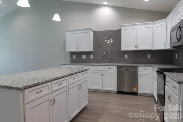 a kitchen with granite countertop a sink a stove and cabinets