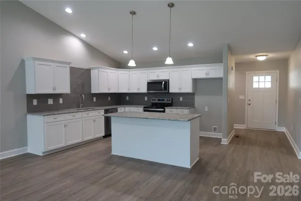 a kitchen with stainless steel appliances granite countertop a sink a stove and a wooden floors