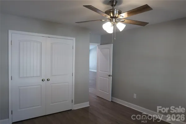an empty room with wooden floor and fan