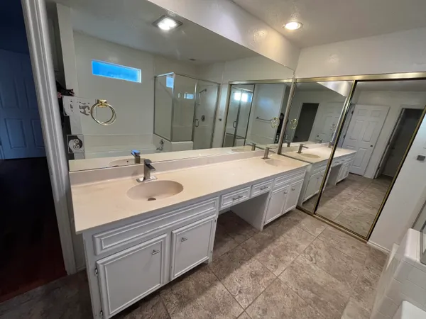 a spacious bathroom with a double vanity sink a mirror and a bathtub