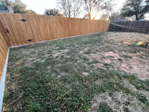 a view of backyard with wooden fence