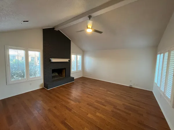 an empty room with windows and fireplace