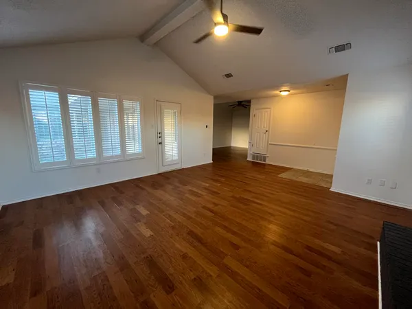 an empty room with wooden floor and windows
