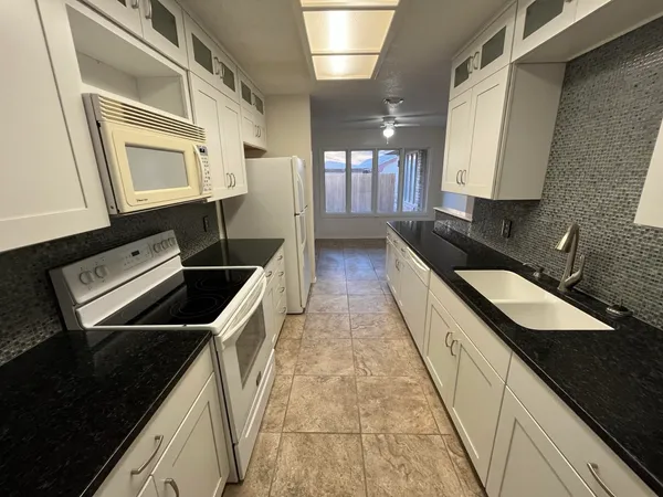 a kitchen with granite countertop stainless steel appliances a sink stove and cabinets