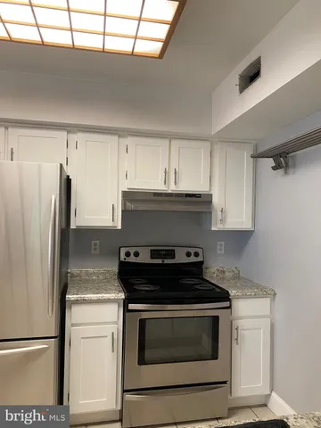 a kitchen with stainless steel appliances granite countertop a stove a refrigerator and a cabinets