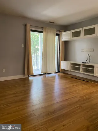 a view of a livingroom with wooden floor and a refrigerator