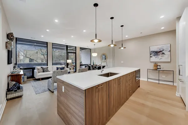 a view of kitchen with kitchen island stainless steel appliances a sink a counter top space and living room view