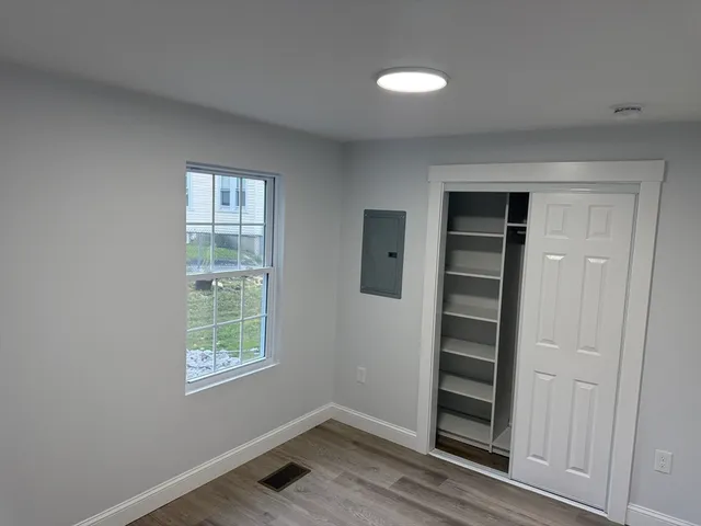 an empty room with wooden floor closet and windows